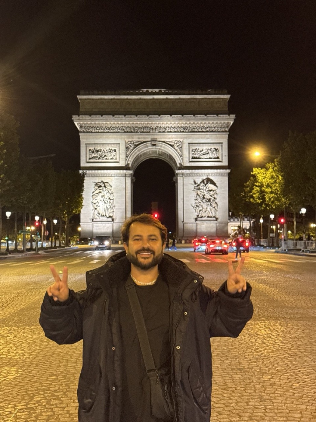 O Dan fazendo paz e amor em frente ao Arco do Triunfo iluminado à noite