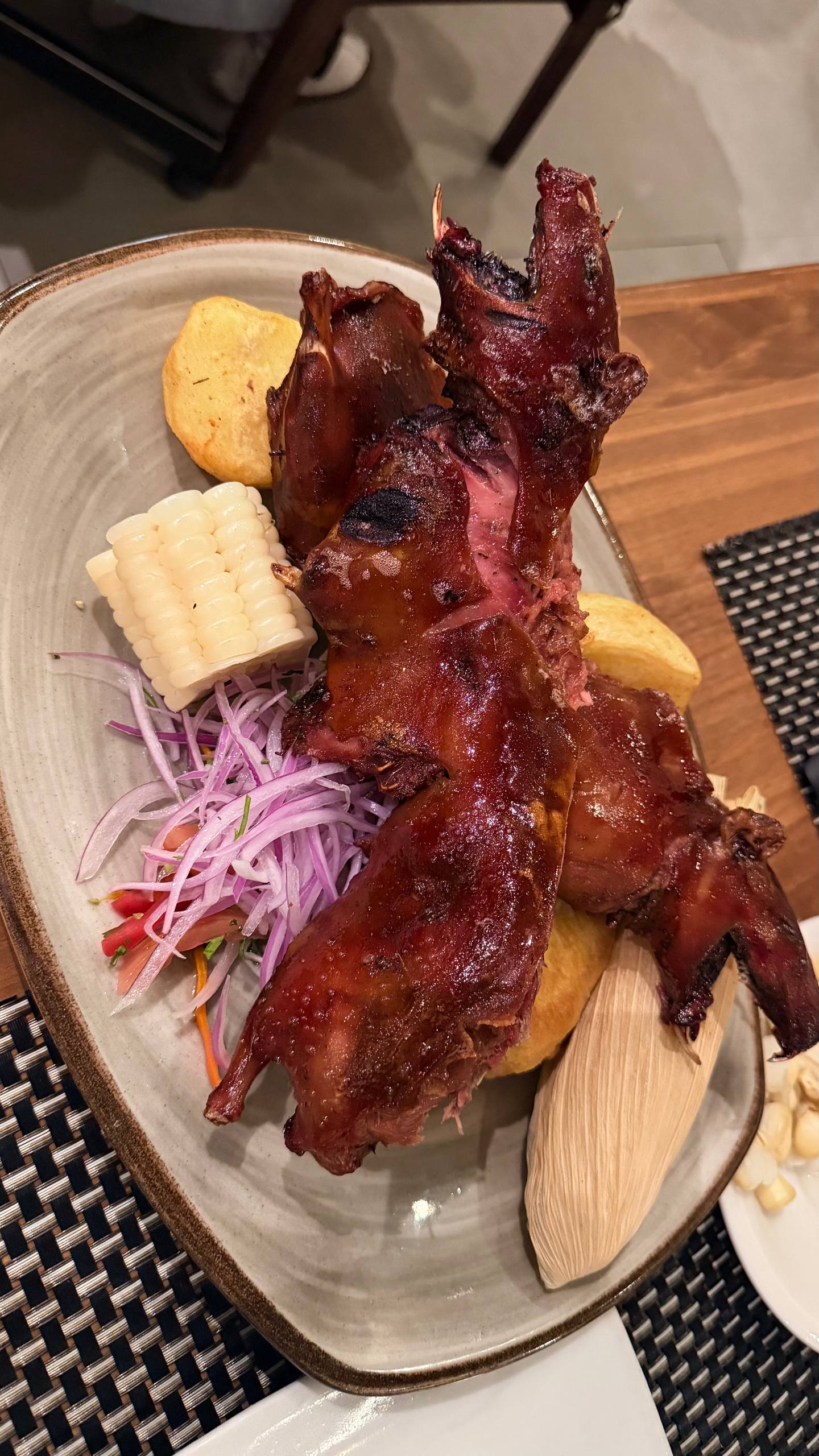 O cuy al horno (porquinho-da-índia assado) inteiro no prato do Andean Grill, com choclo, batata, cebola roxa e tamale