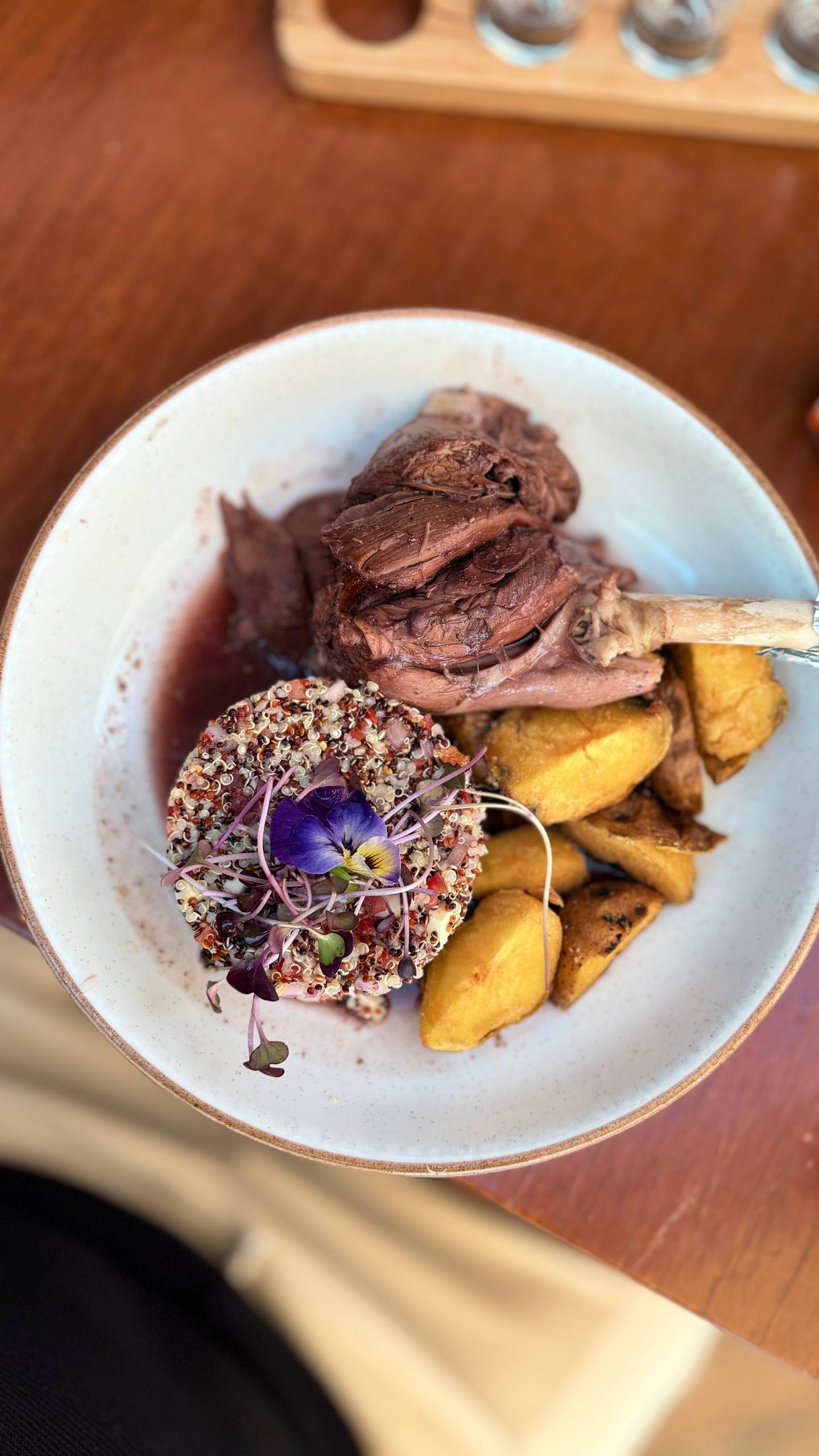 Canilla de cordero do Limbus: joelho de cordeiro que desmancha, com tabule de quinoa decorado com flor comestível e batatas rústicas douradas