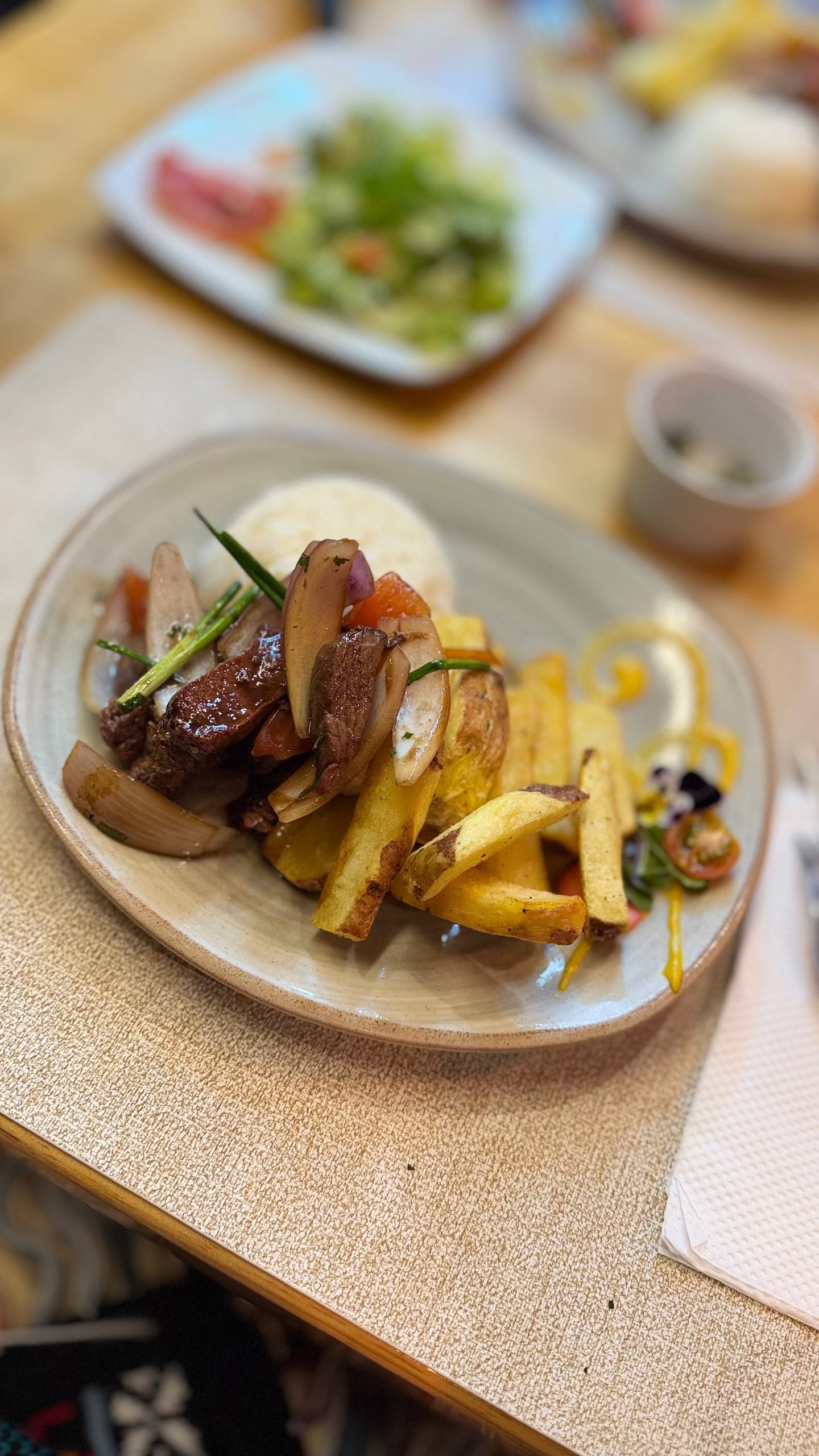 O lomo saltado do menú executivo do Mr. Cuy: tiras de carne salteadas com cebola roxa, tomate e cebolinha, por cima de batatas fritas rústicas, com uma porção de arroz atrás e uma saladinha de guarnição