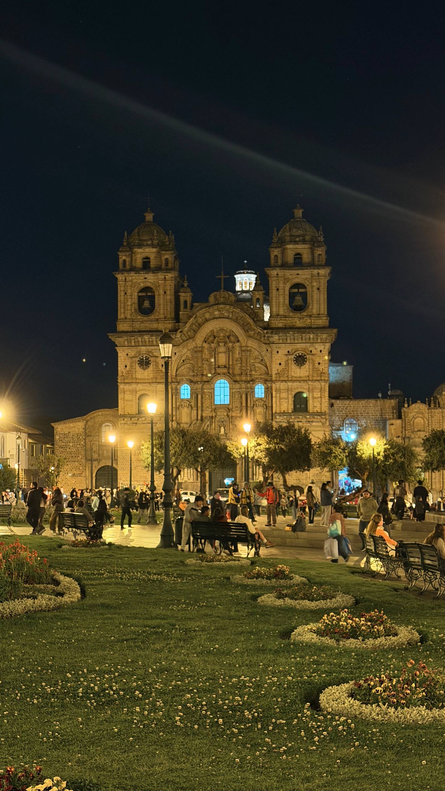 A Plaza de Armas de Cusco à noite: a igreja iluminada, os jardins floridos e a praça cheia de gente