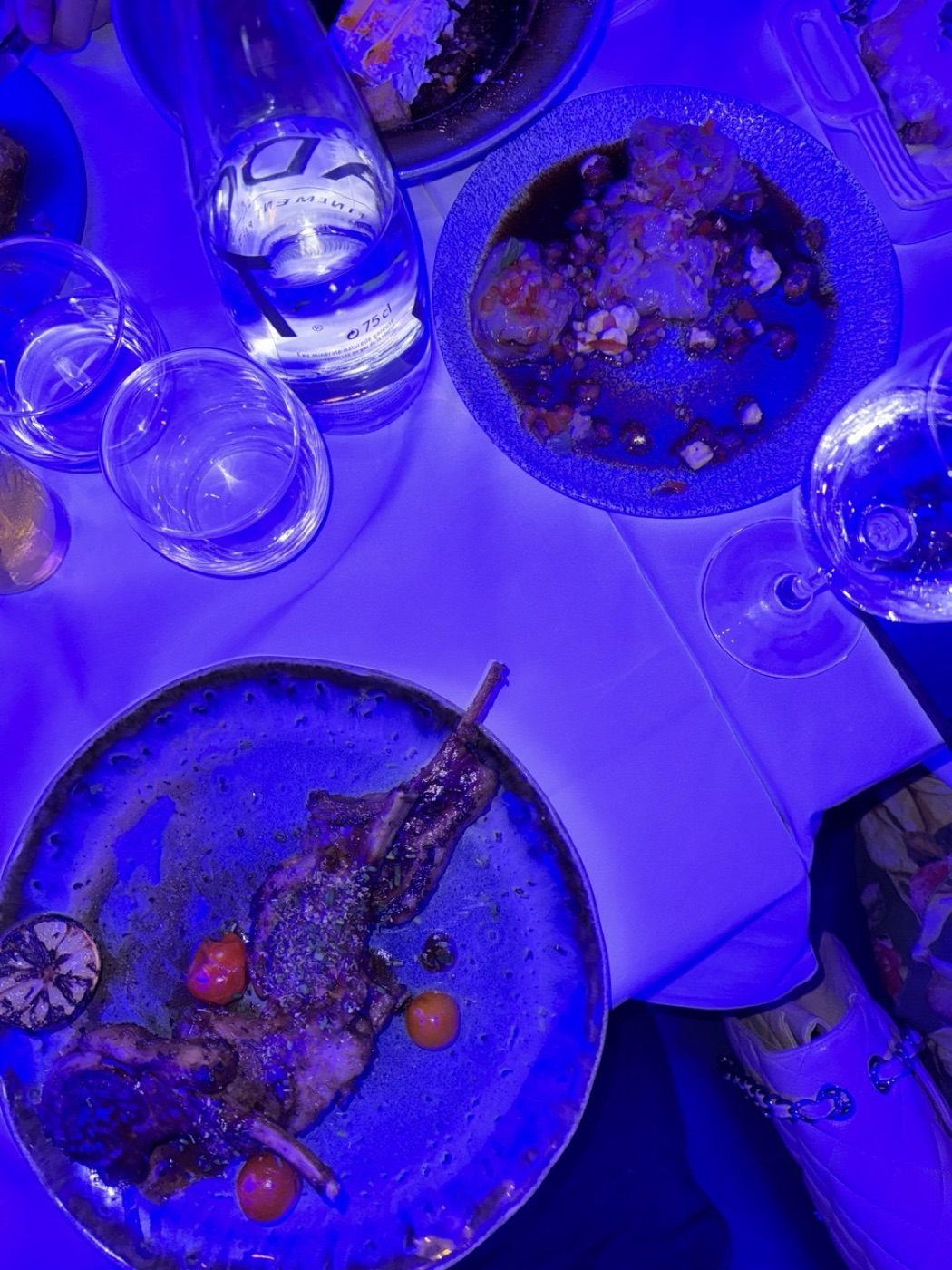 A mesa do Kalamata sob a luz azul do salão, com os pratos gregos servidos