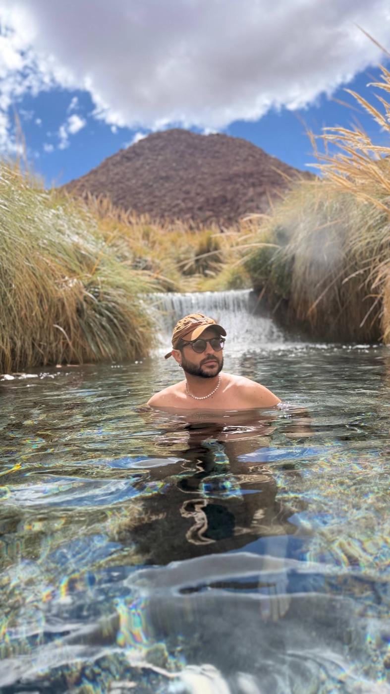 Dan de molho na terma de Puritama, com a cachoeira e o vapor subindo da água quente
